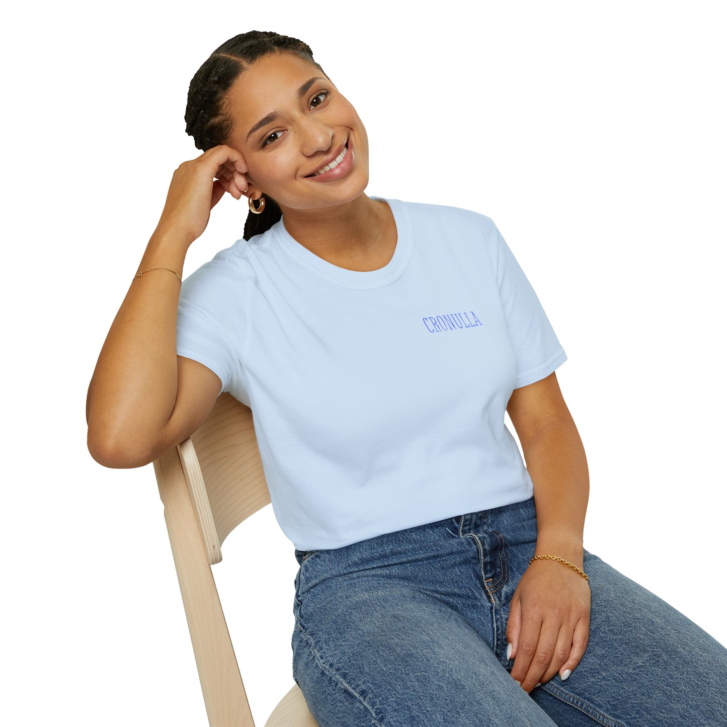 Seated female model wearing pale blue Cronulla Sunrise 'pocket design' photo t-shirt. Front of design features the word "Cronulla" in blue printed in the left front pocket area.