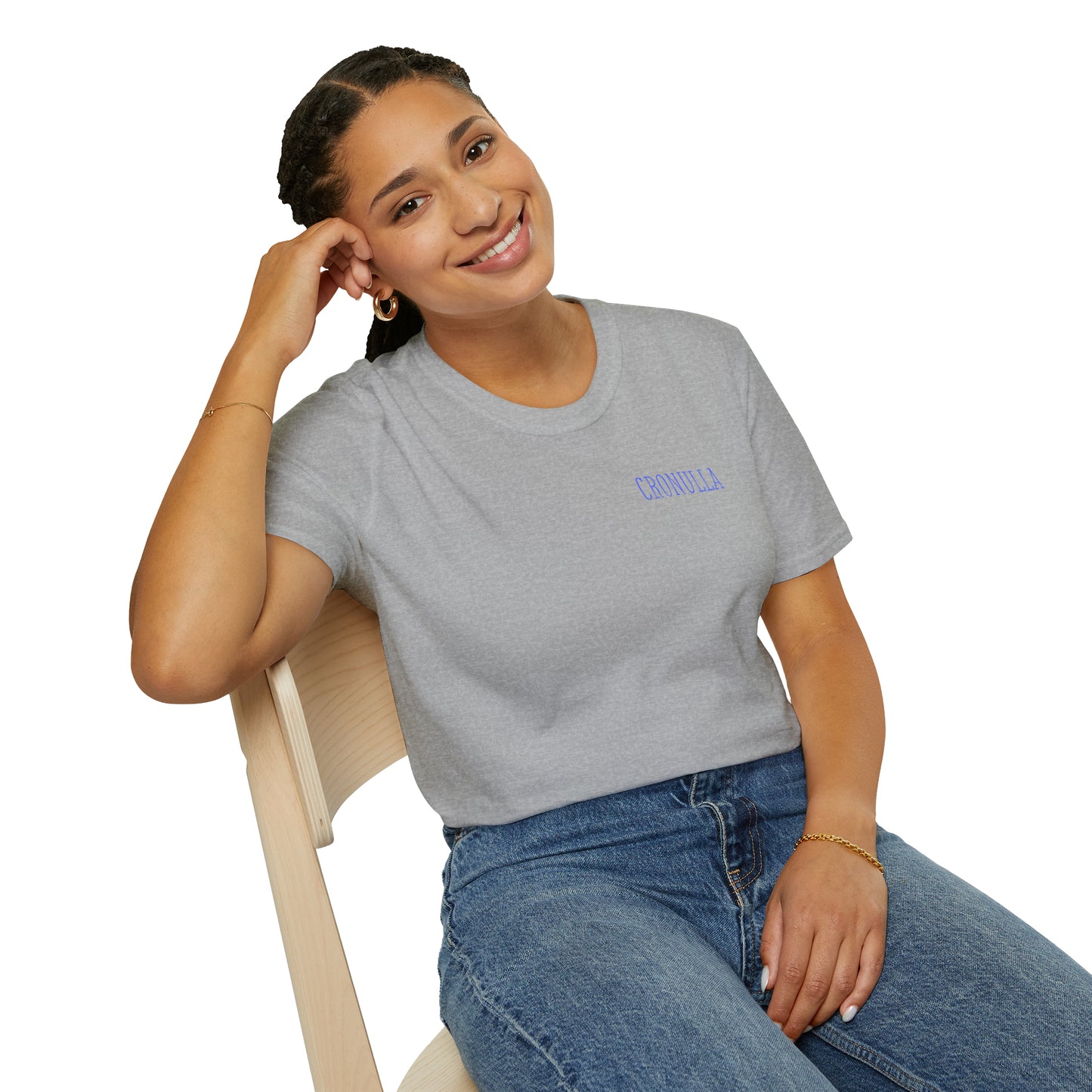 Seated female model wearing grey Cronulla Sunrise 'pocket design' photo t-shirt. Front of design features the word "Cronulla" in blue printed in the left front pocket area.